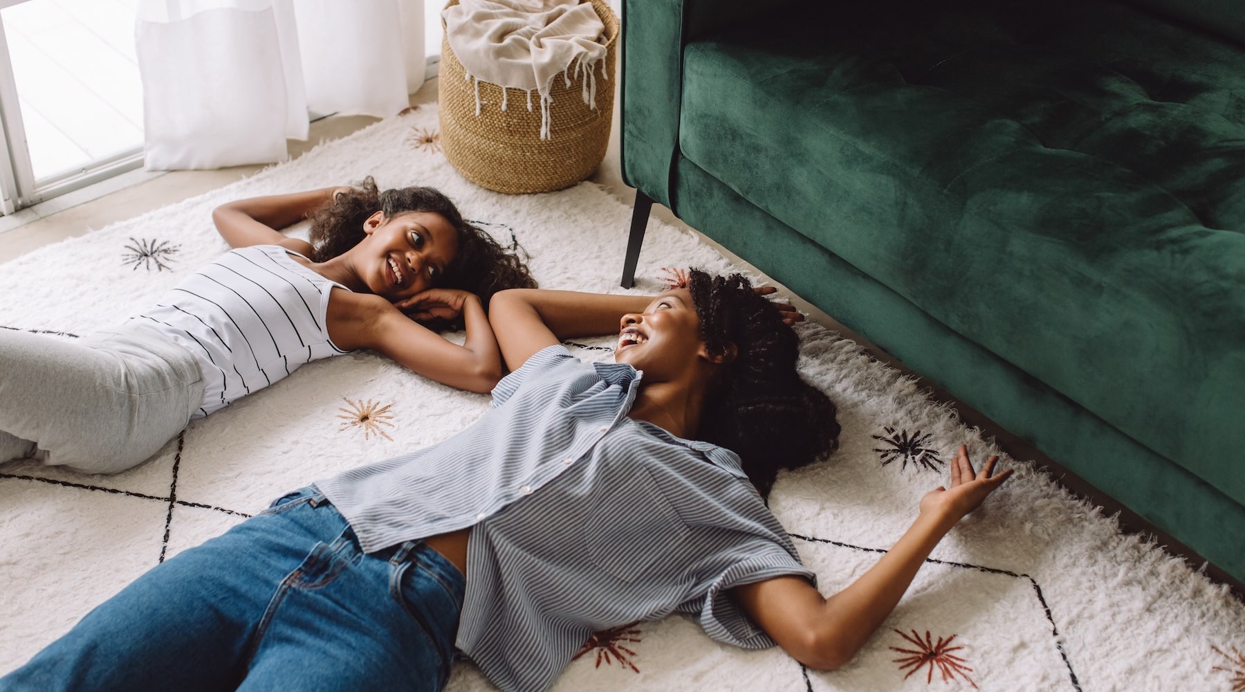 mother and daughter laying on their living room carpet next to couch