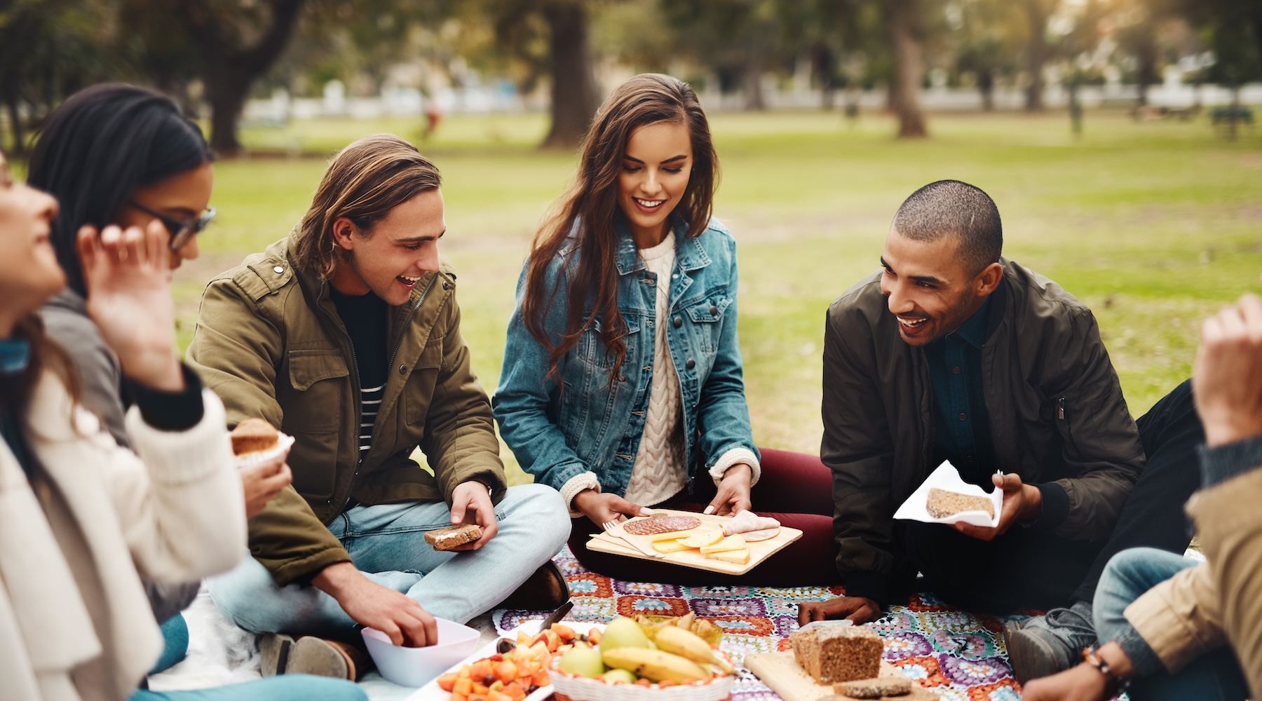 friends eating a picnic together in a park